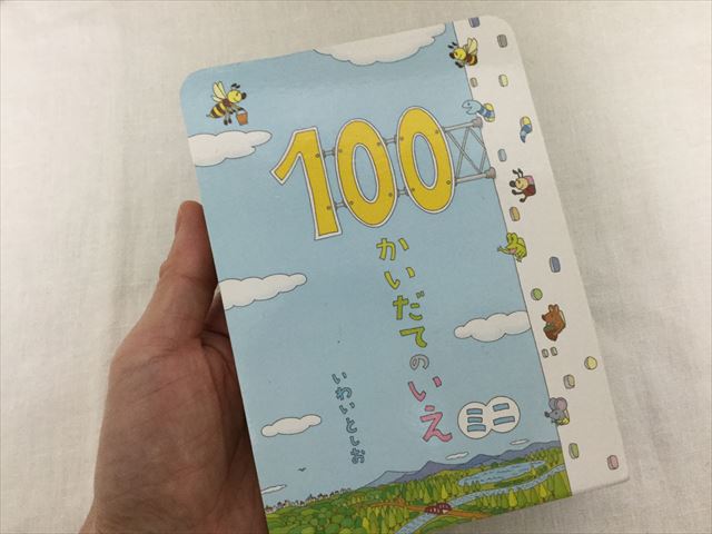 絵本「100かいだてのいえ・ミニ」（偕成社）を手に持ったところ