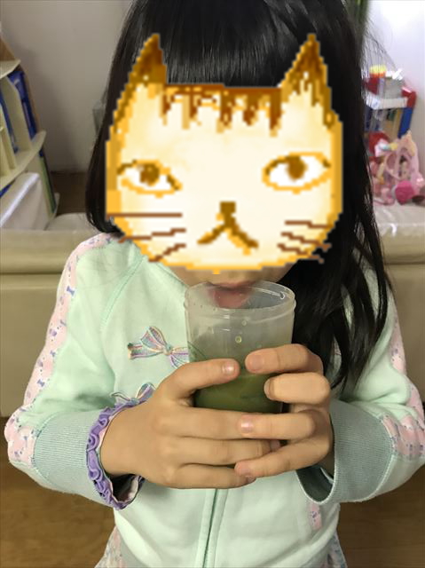 子供が「グリーンミルク」を飲んでいる様子