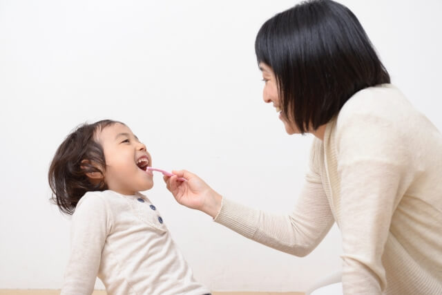 子供に仕上げ磨きをしている親