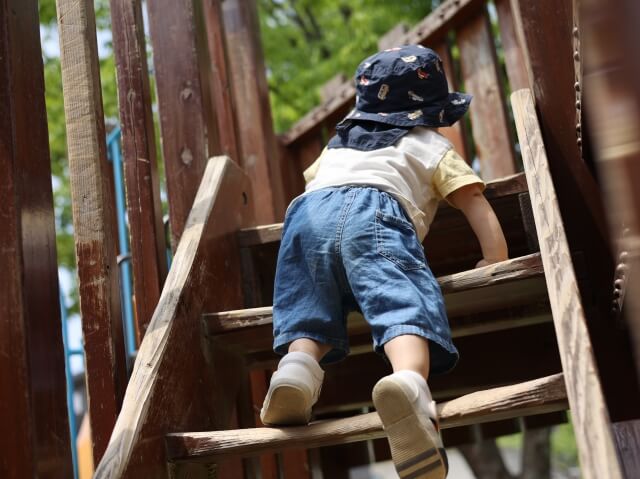 幼児が公園の遊具で遊んでいる